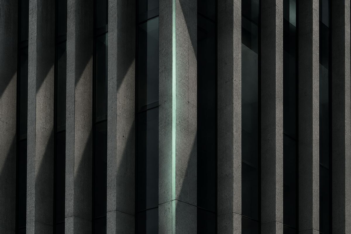 Façade à lames verticales de béton, dont une arête est soulignée par un filet de lumière vert d'eau